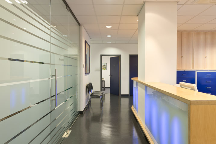 Flur mit Glaswand links und Empfang rechts